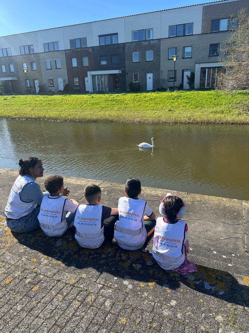 Kinderen van BSO Het Kompasplein zitten samen aan het water in Oosterheem