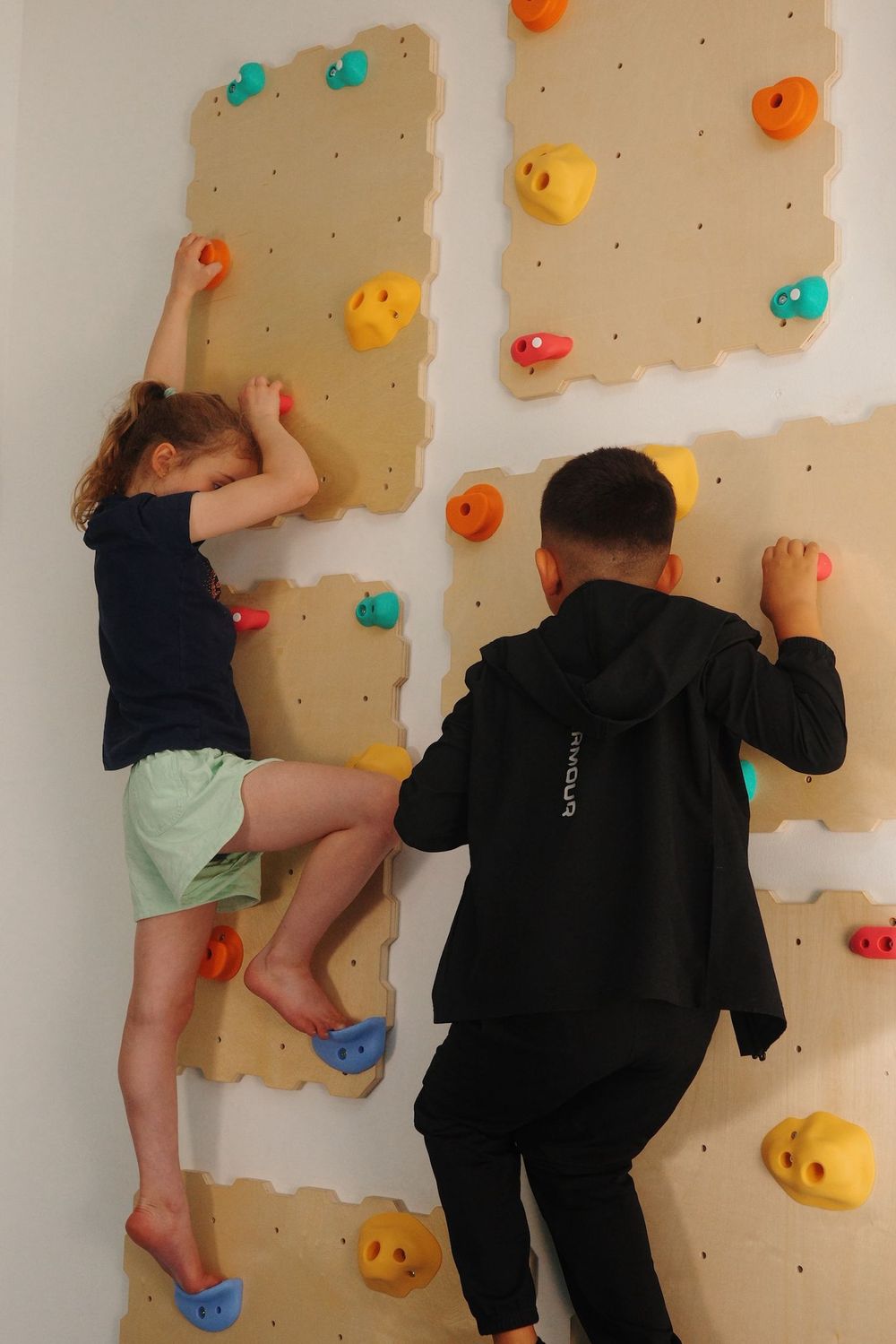Kinderen klimmen op de klimwand in de binnenruimte van BSO Het Kompasplein