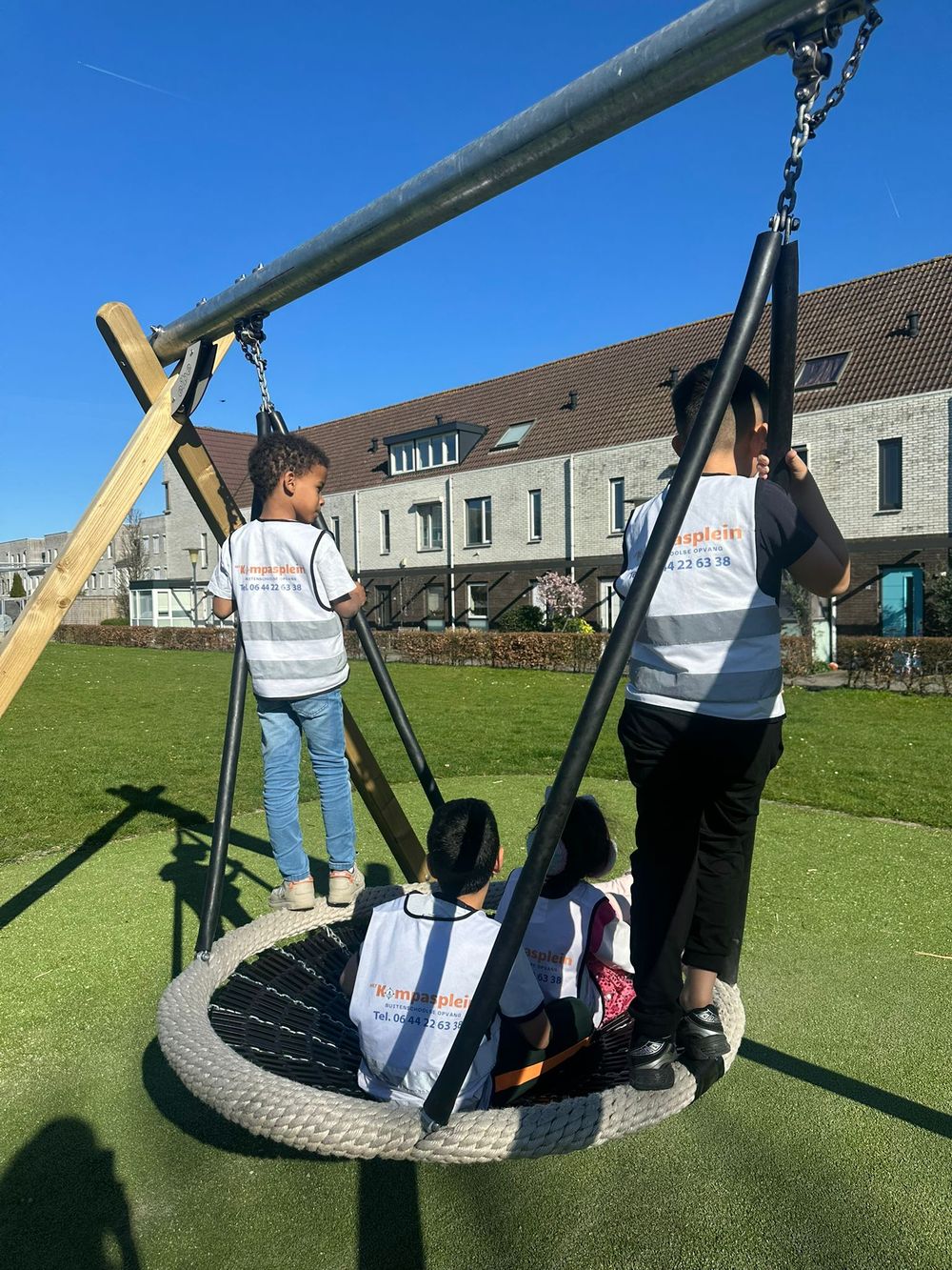 Kinderen spelen samen op de nestschommel tijdens de buitenschoolse opvang