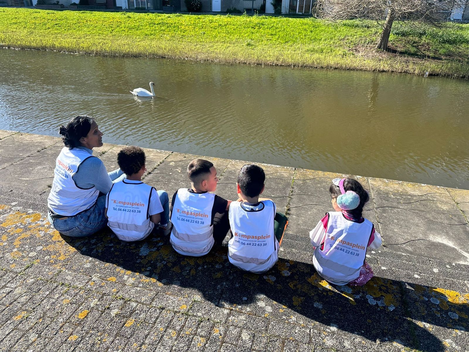 Kinderen van BSO Het Kompasplein kijken naar zwanen aan het water in Oosterheem tijdens de vakantieopvang